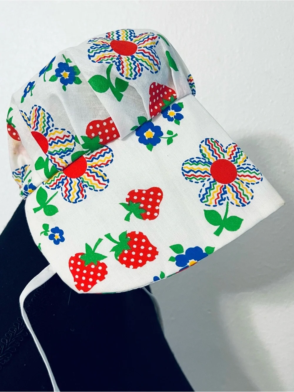 Charming vintage-style baby sunbonnet features a playful white fabric patterned